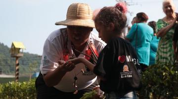 monitora mostrando planta para criança #paratodosverem 