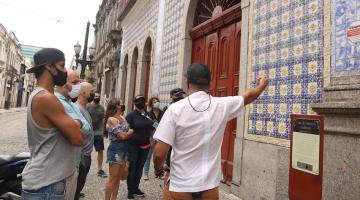 pessoas estão paradas olhando para a fachada da casa da frontaria azulejada. #paratodosverem