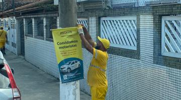 operário usando uniforme retira banner preso em poste. #paratodosverem