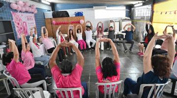 mulheres fazem alongamento sob tenda. #paratodosverem