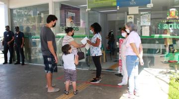 Casal e criança são recepcionados por profissionais na porta da unidade de saúde. #paratodosverem