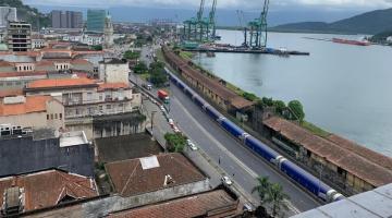 vista aérea da cidade ao lado esquerdo e o porto ao lado direito, como o mar à frente. Há portêineres ao fundo. #paratodosverem