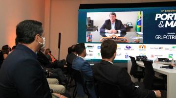 auditório com pessoas sentadas assistindo à apresentação de um ministro no telão. #paratodosverem