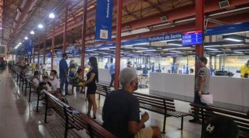 unidade do poupatempo, com pessoas sentadas em bancos. Ambiente é um antigo prédio restaurado, com estruturas aparentes e paineis indicando on