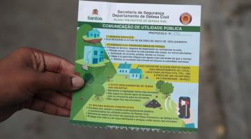 close de mão esquerda segurando folheto informativo da defesa civil. #paratodosverem