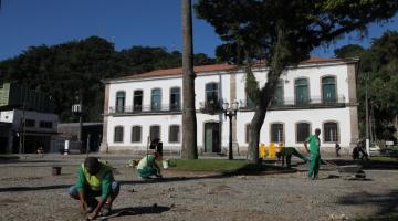 homens trabalhando no assentamento de mosaico com a Cadeia Velha ao fundo. #paratodosverem