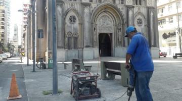 homem usa britadeira sobre piso diante de igreja. #paratodosverem