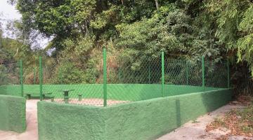 Muro de alvenaria recuperado, com alambrado, pintado na cor verde, com encosta de morro ao fundo. #pratodosverem 