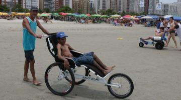 Pessoa com deficiência passeia com triciclo empurrado por monitor. #pracegover