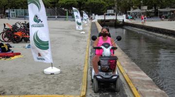 Mulher com veículo adaptado passa pela areia da praia em passarela adaptada #paratodosverem