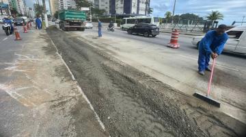 canteiro central de avenida com caminhào ao fundo. a área está delimitada por cones. Há um homem trabalhando na obra, ao lado direito da imagem. #paratodosverem 