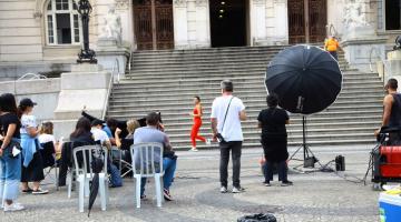 Equipe de filmagem, com equipamentos filma cena diante da escadaria de acesso à prefeitura, na praça mauá. #paratodosverem