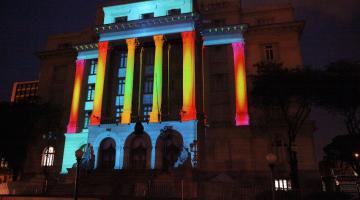 a fachada da prefeitura à noite com projeção colorida. #paratodosverem
