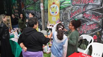 pessoas olhando artesanato em barraca #paratodosverem