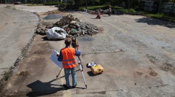 homemm uniformizado está atrás de equipamento de sondagem em terreno com piso quebrado. #paratodosverem