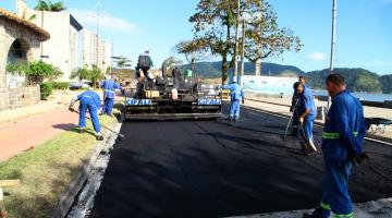 Máquina pavimentadora passa em trecho da avenida da orla em frente ao Aquário. Homens trabalham nos retoques. #Pracegover