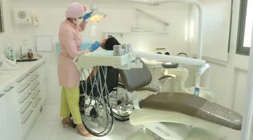 Em um consultório, dentista atende mulher em uma cadeira de rodas. #paratodosverem