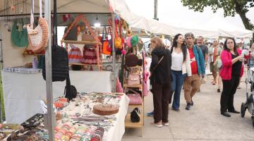pessoas circulam por barracas de artesanato. #paratodosverem