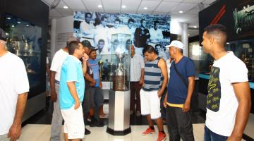 homens olham para troféus no memorial do Santos #pracegover 