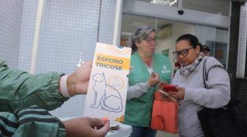 em primeiro plano, panfleto da doença e ao fundo pessoa atendida #paratodosverem