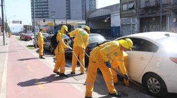 homens varrem guia de calçada. #paratodosverem 