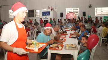 pessoas se servindo enquanto homem de gorro passa com bandeja #paratodosverem