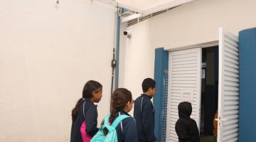 alunos entram em sala. no alto da parede há uma câmera. #paratodosverem
