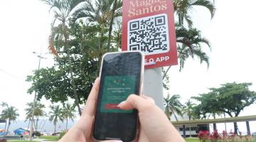 pessoa aponta celular para poste com QR code #paratodosverem