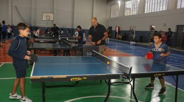crinças jogam tênis de mesa em quadra. #paratodosverem