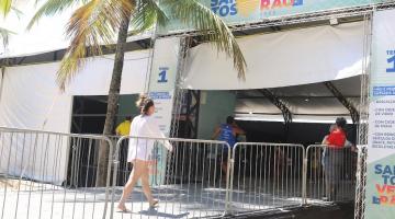 a fachada de uma tenda onde se lê no alto Santos Verão. Uma mulher está entrando no recinto. #paratodosverem 
