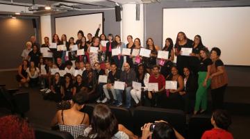 alunos posa para foto de pé no palco e segurando seus certificados. #paratodosverem 