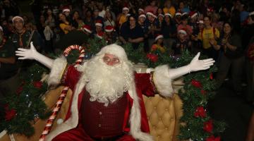 papai noel de braços abertos com grande público ao fundo. #paratodosverem