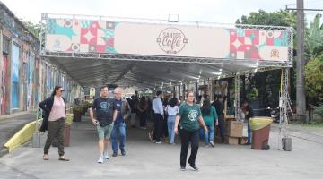 pessoas estaõ circulando sob tenda com fachada onde se lê Festival Santos Café 2024. #paratodosverem 