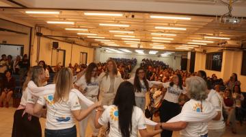 mulheres fazem roda e se abraçam diante de palco. #paratodosverem