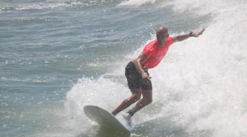 surfista equilibra-se em cima de uma prancha de longboard #paratodosverem