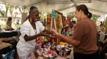 artesã apresenta produtos para consumidora em feira criativa. #paratodosverem