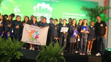 crianças seguram bandeira em palco #paratodosverem