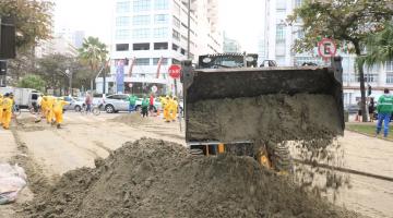 homens e máquina limpam trecho de calçadão e areia da praia. #paratodosverem