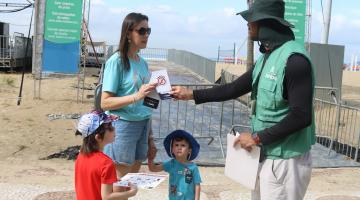 Folheto de conscientização é entregue na praia. #Paratodosverem