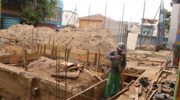 fundação de terreno para construção de prédio. Homem está trabalhando na armação de madeira subterranea. #paratodosverem 