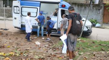 pessoas se aproximam de consultório montado em van estacionada na rua. #paratodosverem