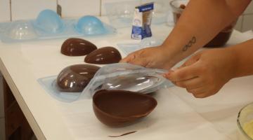 mãos desenformam ovo de chocolate. #paratodosverem 