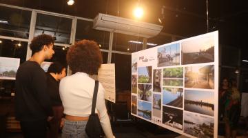 pessoas observam fotos em exposição. #paratodosverem