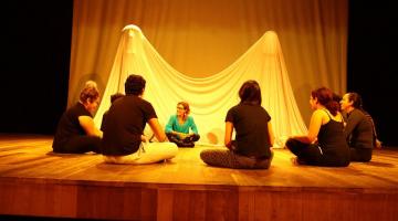 alunos de teatro estão sentado no palco conversando. #paratodosverem 