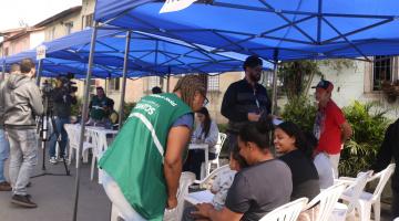 agente uniformizada atende pessoas sob tenda de triagem. #paratodosverem 