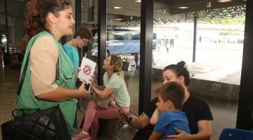 Imagem da agente orientando pessoas na Rodovária. #Paratodosverem.