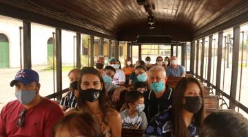 Pessoas sentadas dentro do bonde turístico #paratodosverem