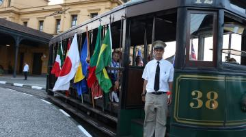 bonde com pessoas segurando bandeiras de países #paratodosverem