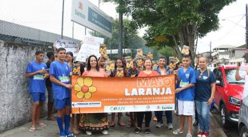 alunos na rua em frente a escola mostram cartaz da campanha #paratodosverem