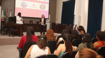 mulheres sentadas em auditório assistem palestra. #paratodosverem 
